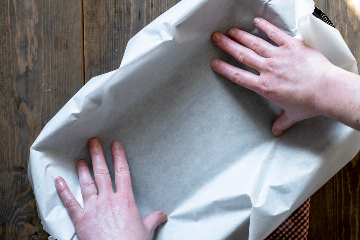 placing parchment paper into cast iron casserole pan.