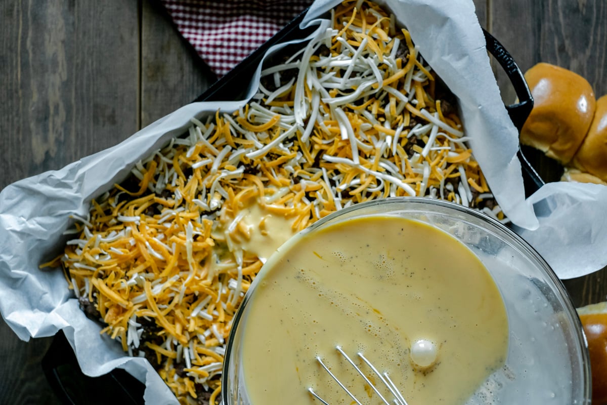 pouring eggs into breakfast strata.