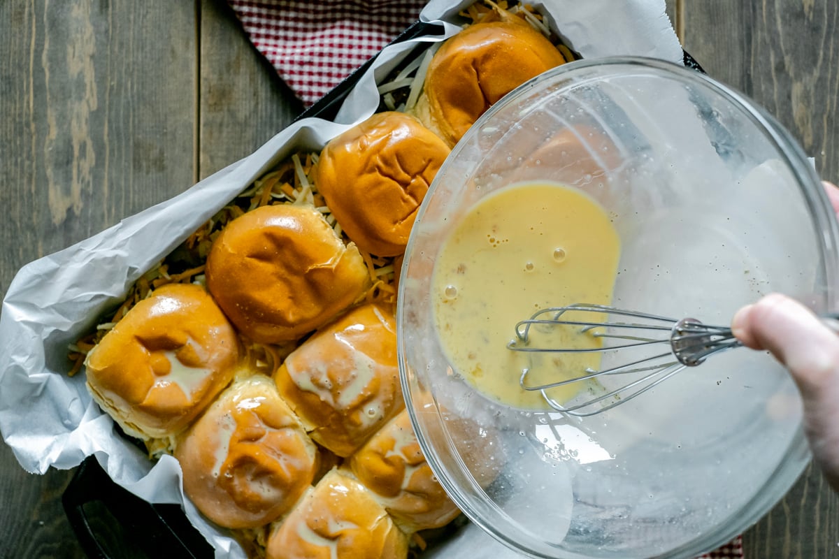 pouring eggs over top of breakfast strata.