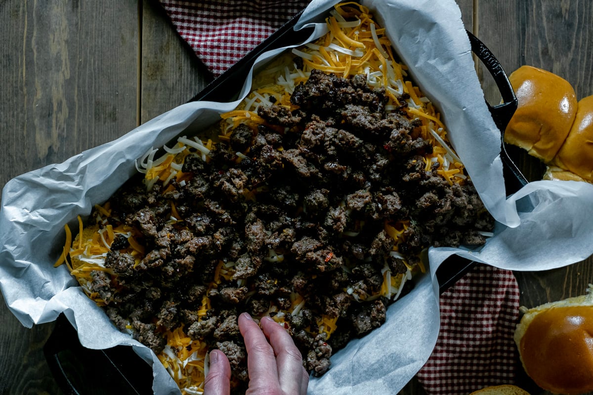 spreading sausage over cheese in casserole dish.