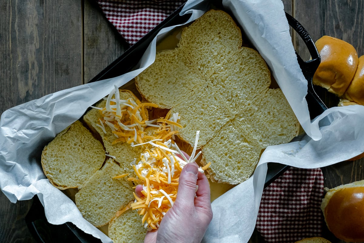 sprinkling cheese over brioche rolls.