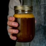 hand holding jar of wild game stock.