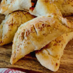 hand pies with sesame seeds on wood board.