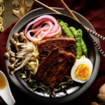 pork belly ramen in bowl with chopsticks.