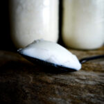 pork lard on spoon with jars in background.