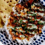 pronghorn curry over rice with green sauce on top.
