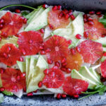slices of blood orange and avocado in black bowl.