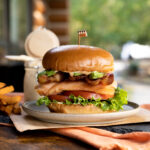 smoked trout BLT sandwich on plate with outdoor background.