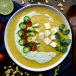 sopa de maiz in white bowl with fresh toppings.