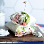 venison steak salad wrap on wood board.