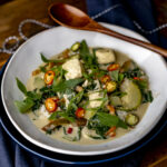 halibut green curry in white bowl with wood spoon.