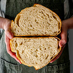 hands holding two halves of sourdough loaf inside view.