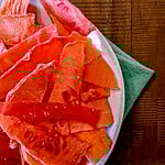watermelon jerky in white bowl with green towel.