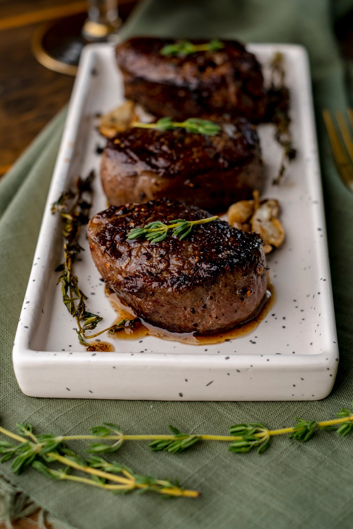 3 elk tenderloin medallions on white plate with thyme.