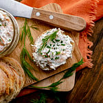 smoked trout dip on baguette with wooden spreader.