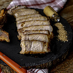 sliced pork chop on slate board with red and white cloth.