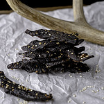 stack of teriyaki venison jerky on parchment paper with antler in background.