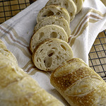 sourdough baguette with slices on tea towel.