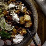 bowl of pozole rojo with venison and fresh toppings with spoon.