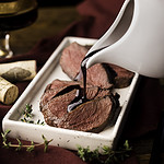 pouring port wine reduction over sliced sandhill crane breast.