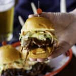 hand holding BBQ venison slider with coleslaw.