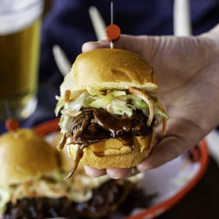 hand holding BBQ venison slider with coleslaw.