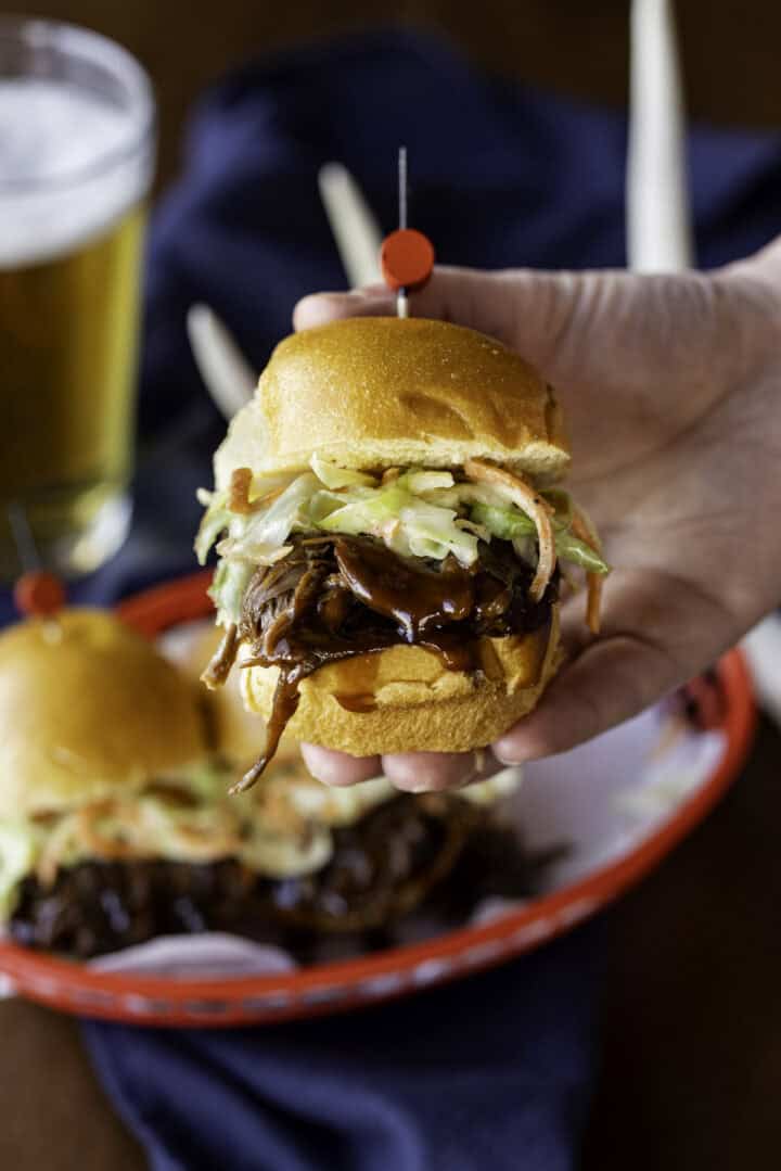 hand holding BBQ venison slider with coleslaw.
