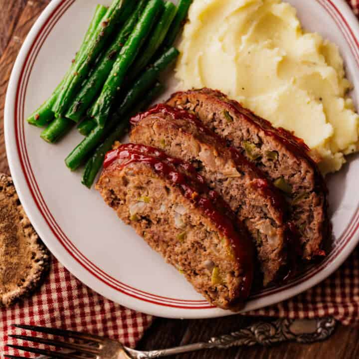 3 slices of elk meatloaf with green beans and mashed potatoes.