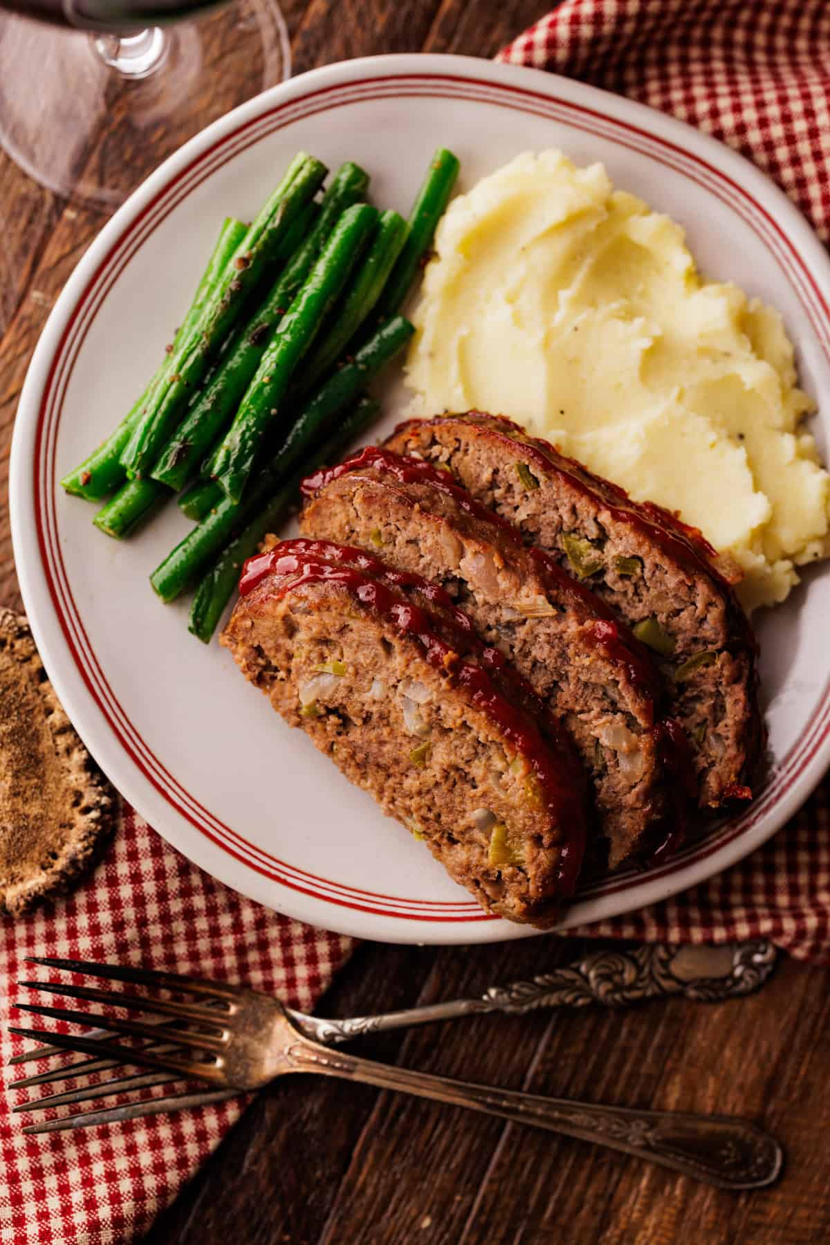 3 slices of elk meatloaf with green beans and mashed potatoes.