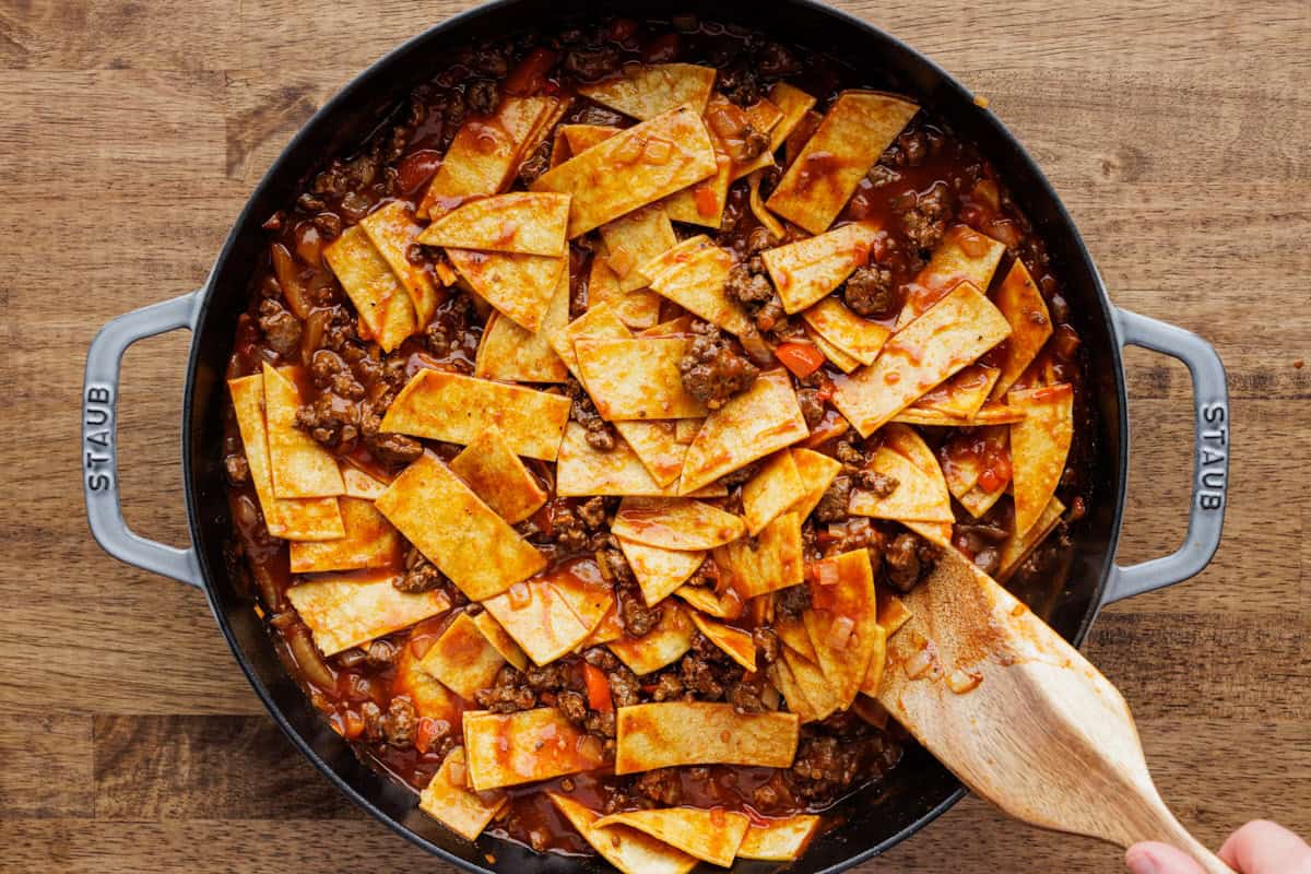 mixing enchilada filling with tortilla strips.
