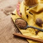 spoonful of jerk seasoning on yellow cloth with spices.
