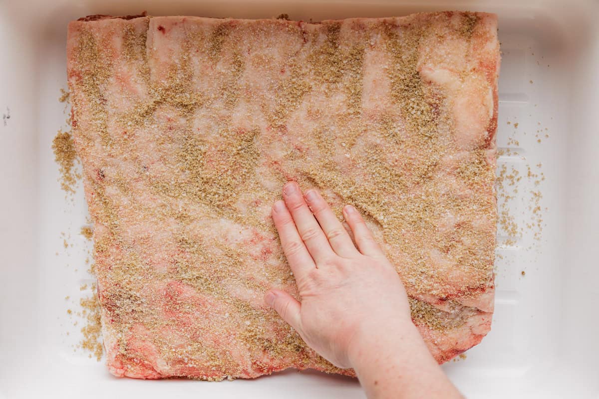 patting cure mixture onto pork belly.