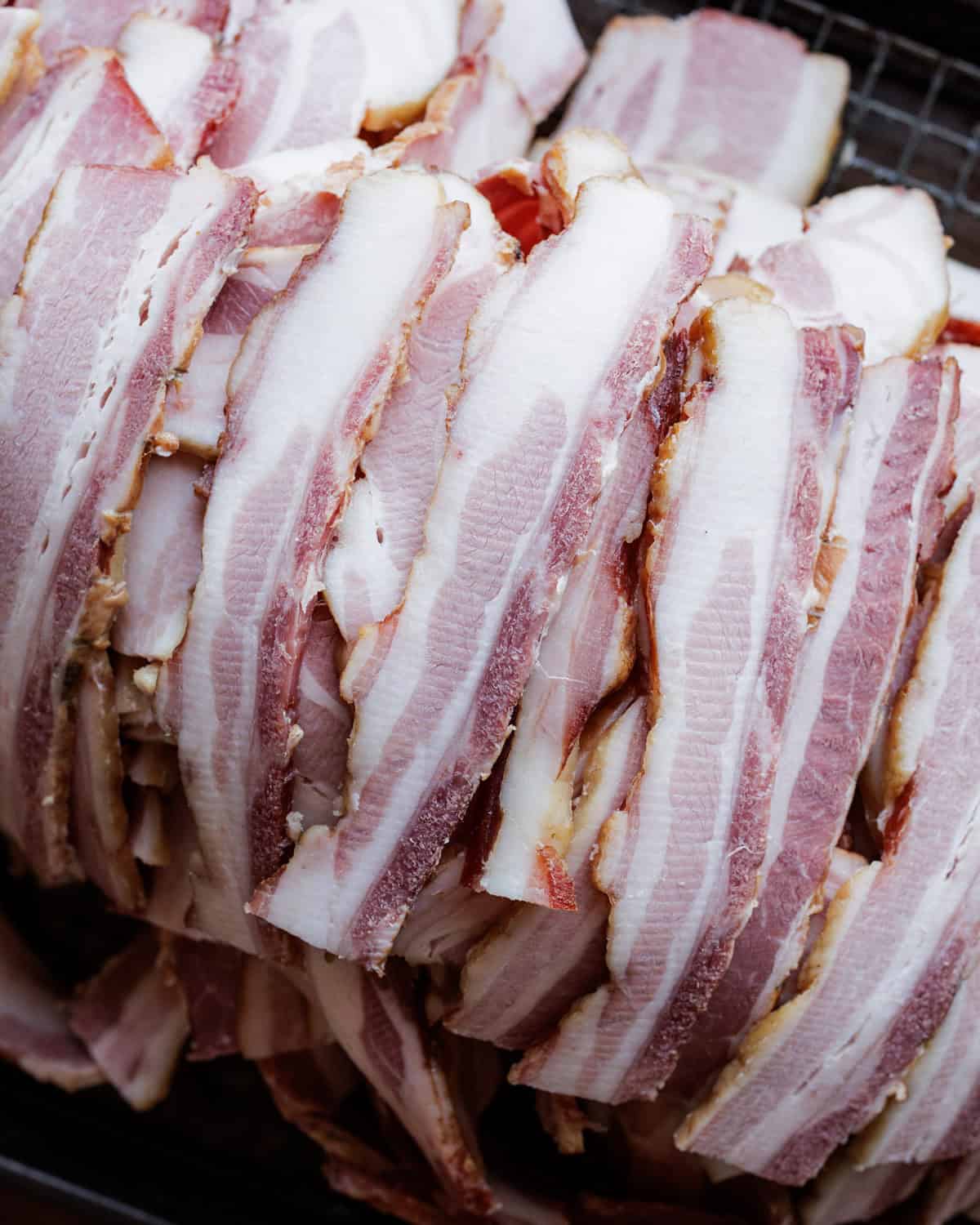 slices of homemade smoked bacon in pile.