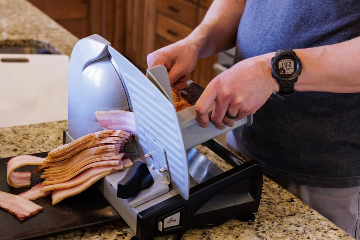 slicing slab of bacon with meat slicer.