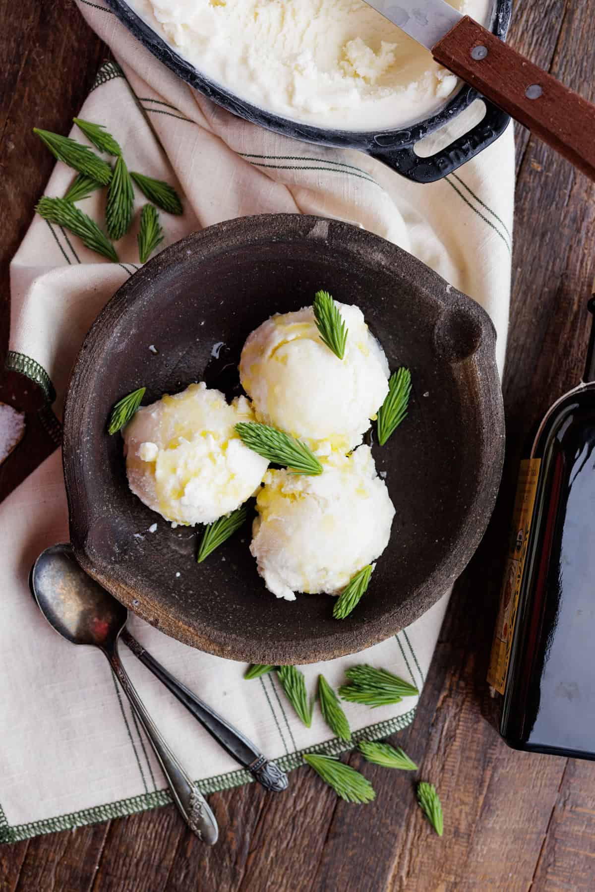 scoops of spruce tip olive oil ice cream in brown bowl.