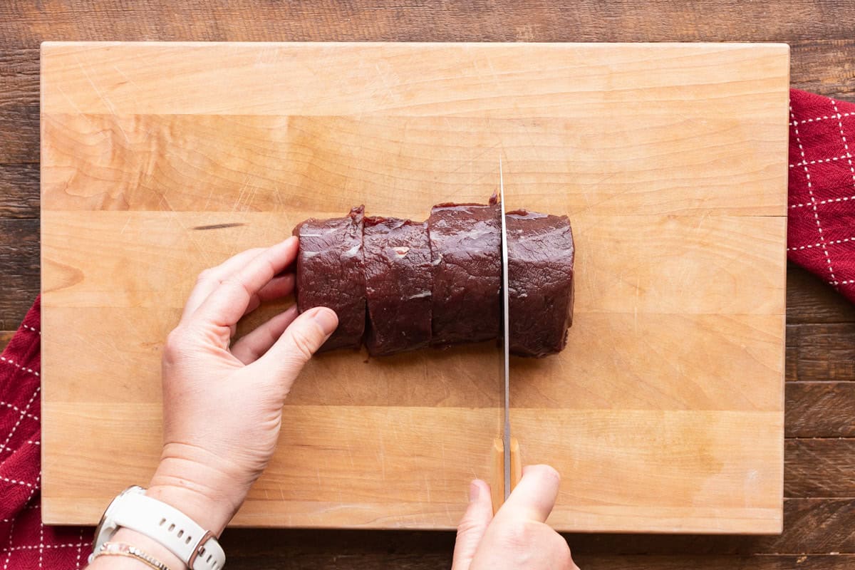 cutting venison backstrap into 4 medallions.