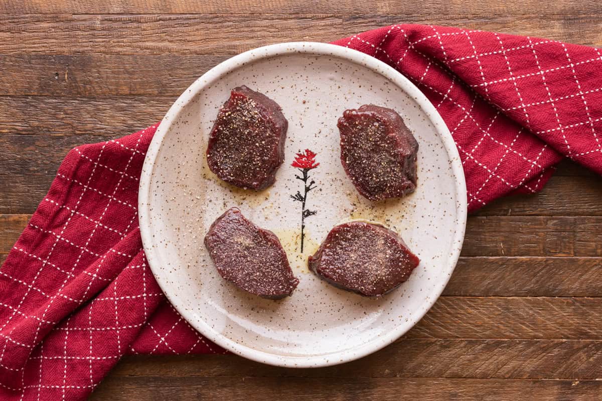 seasoned venison backstrap medallions on plate.