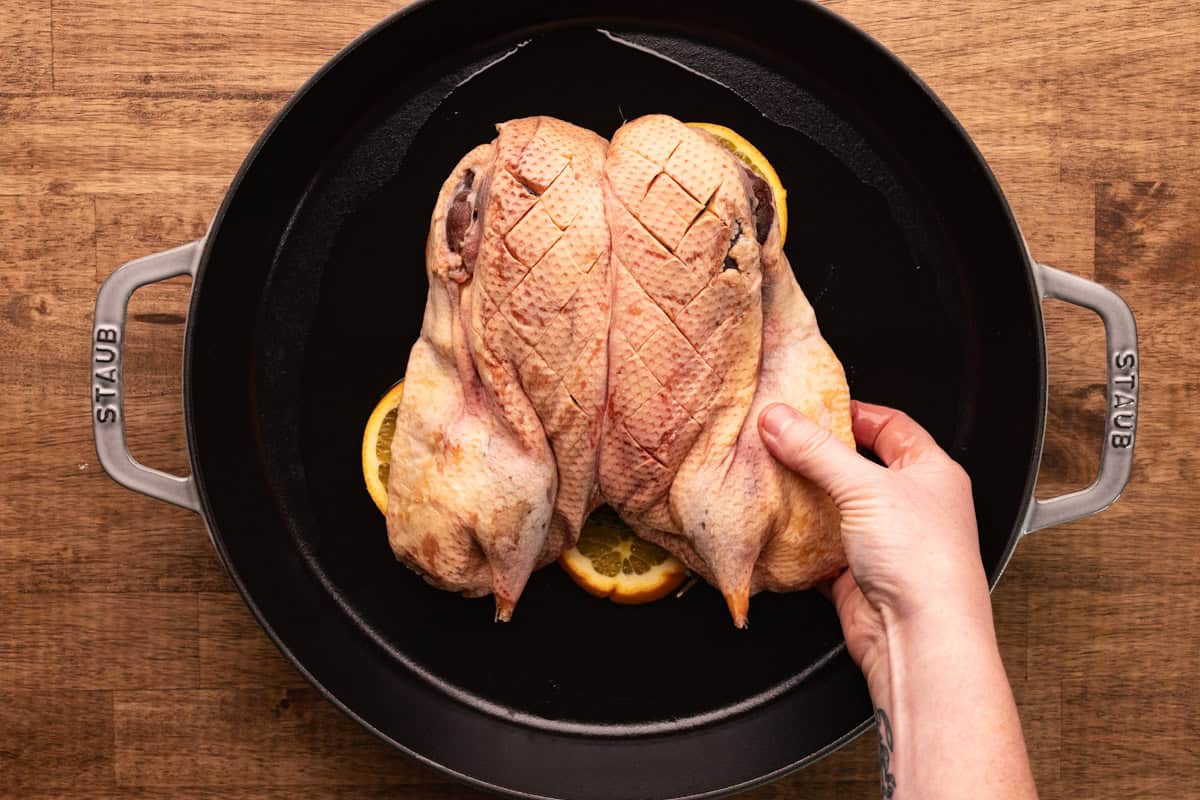 placing duck in cast iron pan.