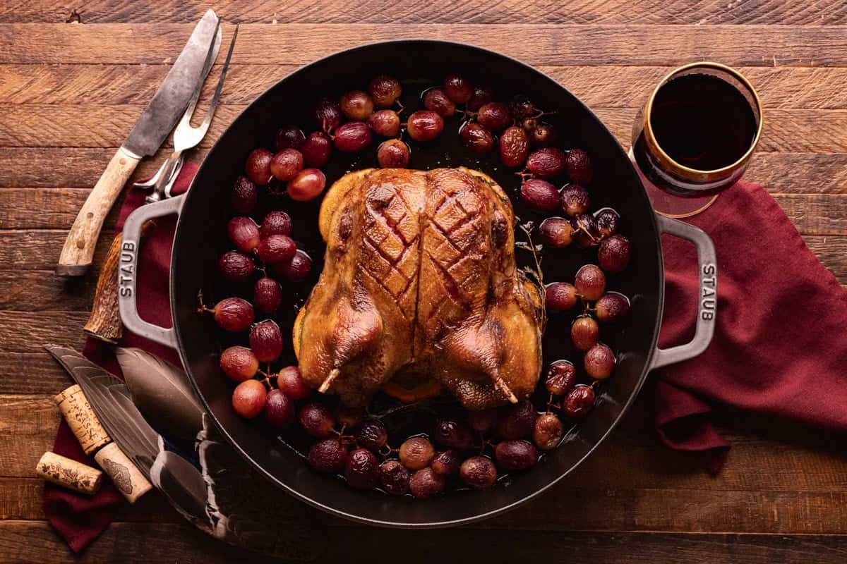 roasted duck with grapes in pan.