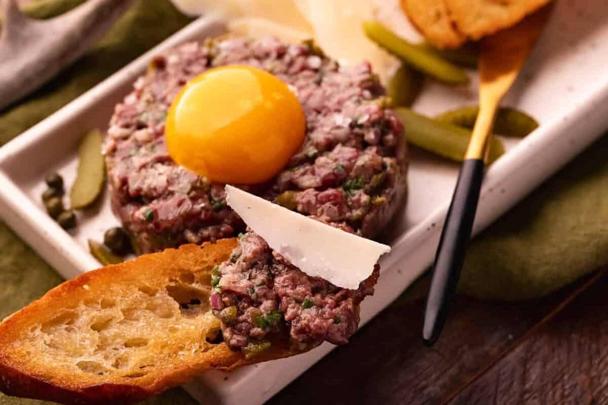 venison tartare on baguette slice with parmesan.