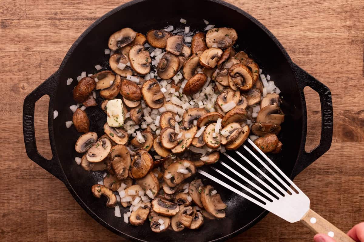 cooking mushrooms with onions in cast iron skillet.