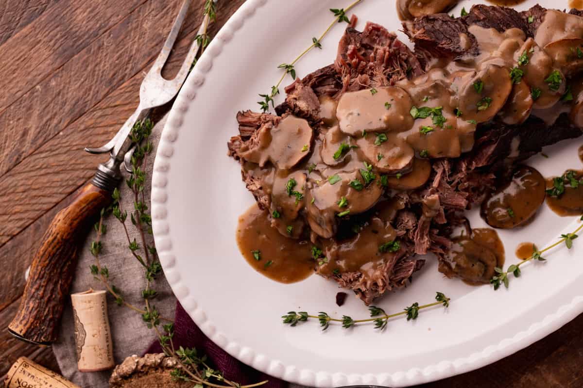 crock pot elk roast on plate with mushroom gravy.