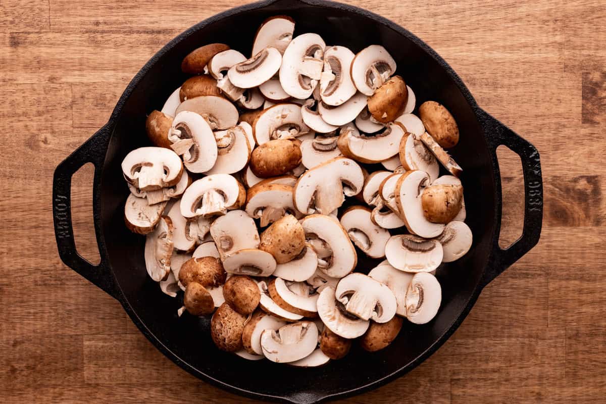 sliced mushrooms in cast iron skillet.