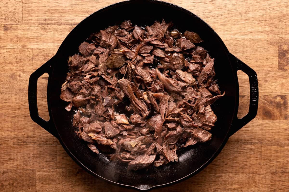venison carnitas cooking in skillet.
