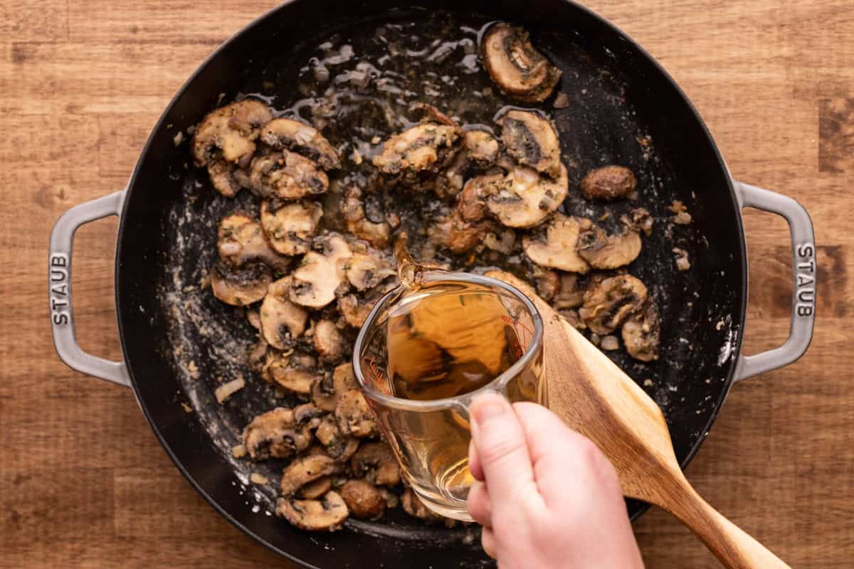 pouring marsala wine into skillet with mushrooms.