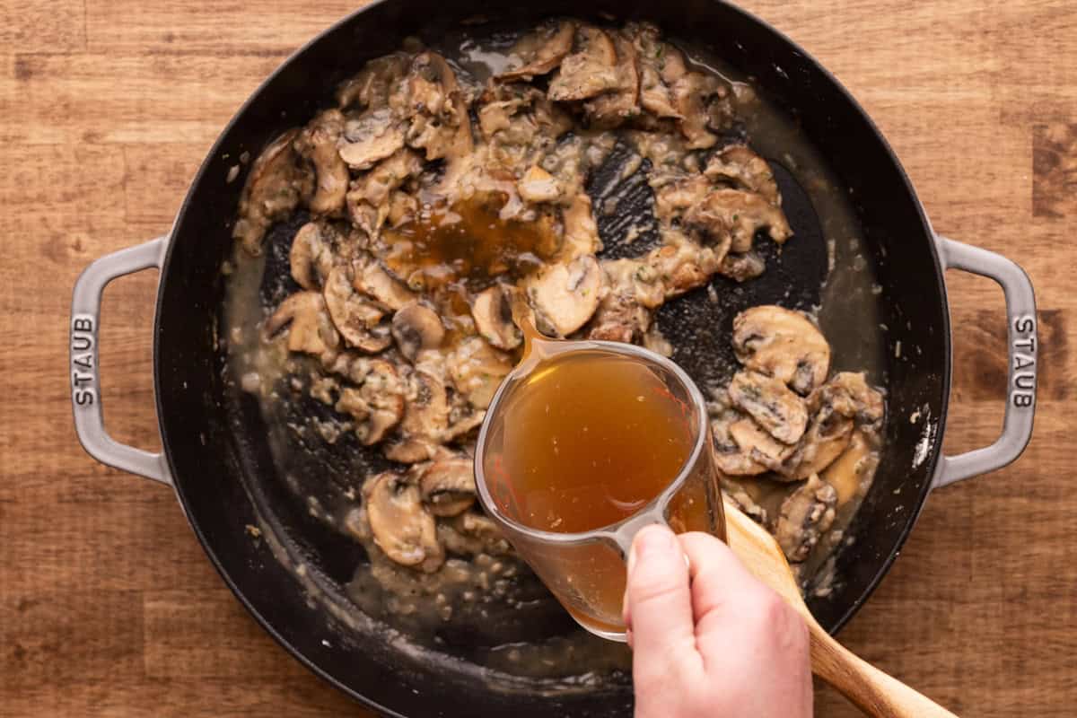 pouring stock into pan with mushrooms.