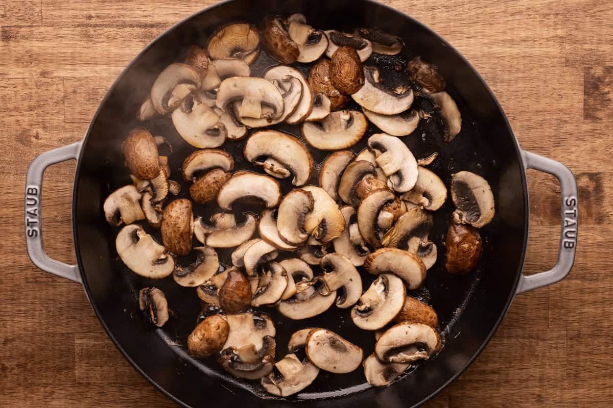 sliced mushrooms cooking in skillet.