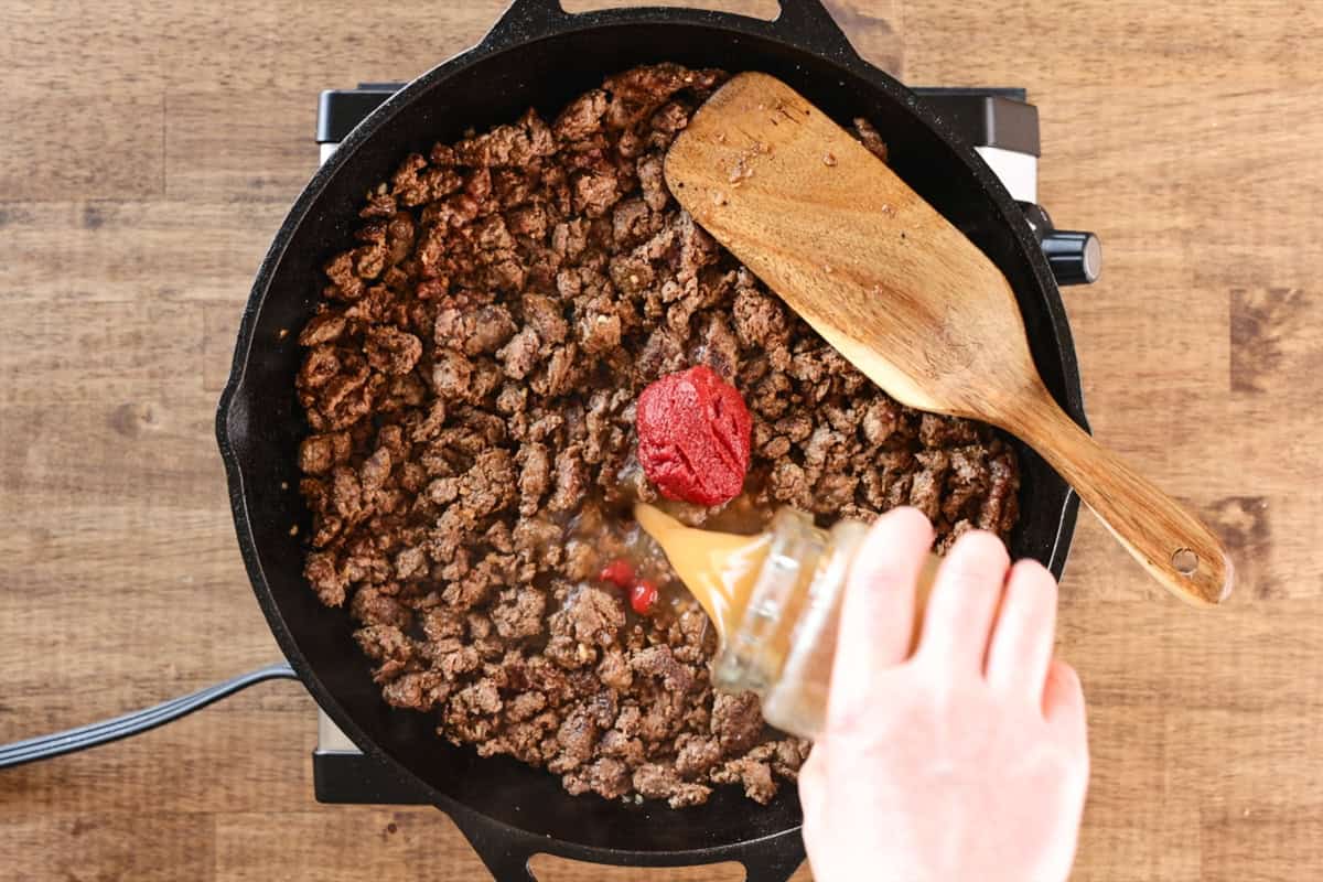 pouring stock into pan of venison taco meat.