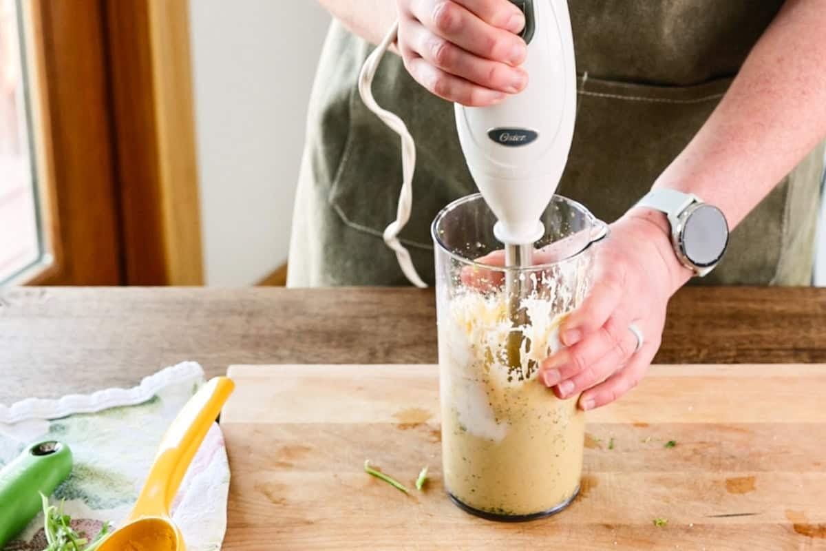 using immersion blender to blend chipotle lime dressing.