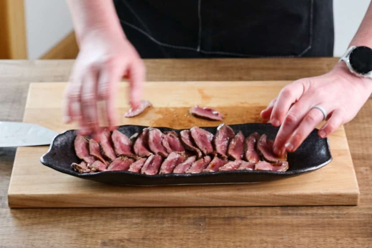 arranging venison tataki on serving dish.